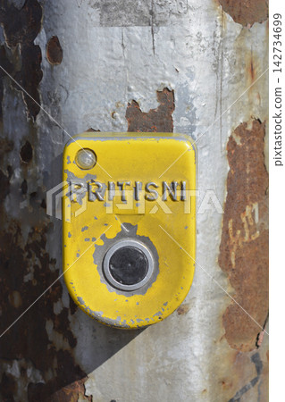 Yellow pedestrian crossing button on rusty pole Yellow pedestrian crossing button on rusty pole 142734699