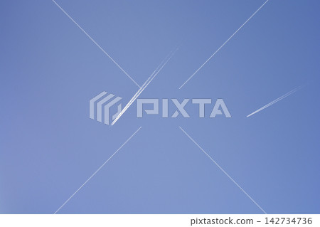Two airplane contrails flying across a clear blue sky Two airplane contrails flying across a clear blue sky 142734736