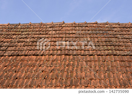 Old clay tile roof against blue sky 142735090