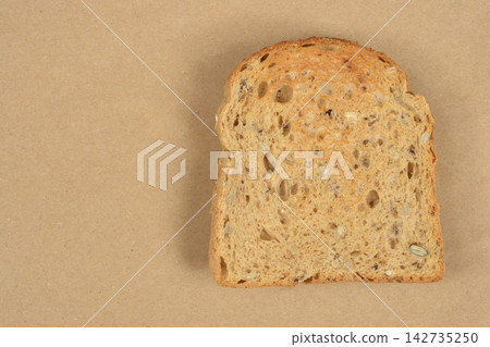 Toasted Whole Grain Bread Slice on Brown Background Toasted Whole Grain Bread Slice on Brown Background 142735250