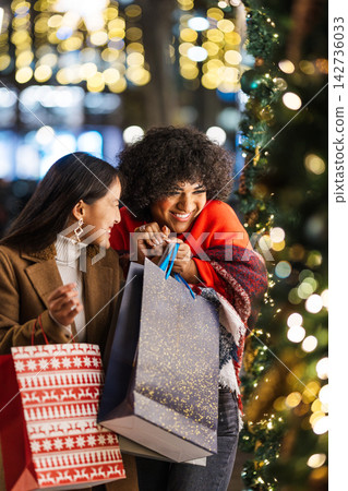 Two happy young women enjoying christmas shopping in the city at night Two happy young women enjoying christmas shopping in the city at night 142736033