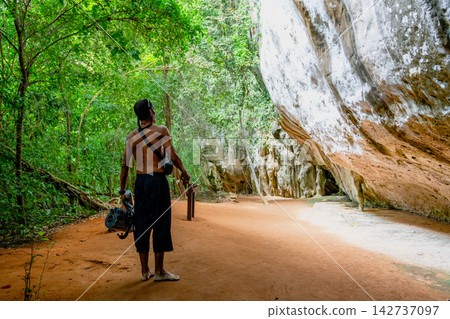 Explorer walking along dirt path beside rock formation Explorer walking along dirt path beside rock formation 142737097