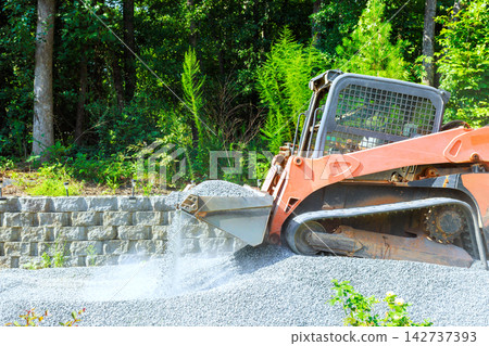 Construction equipment moves gravel in forested area Construction equipment moves gravel in forested area 142737393