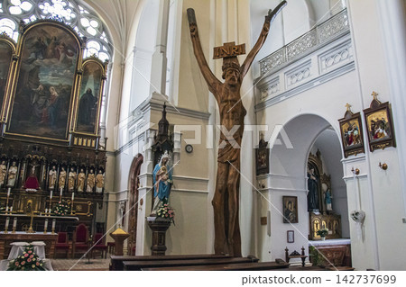 Nitra, Slovakia - May 23, 2024: Monumental Wooden Crucifix and Main Altar Inside a Catholic Church Nitra, Slovakia - May 23, 2024: Monumental Wooden Crucifix and Main Altar Inside a Catholic Church 142737699