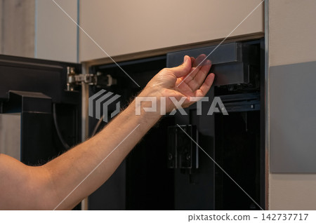 Hand removing coffee machine water reservoir from modern kitchen appliance for cleaning Hand removing coffee machine water reservoir from modern kitchen appliance for cleaning 142737717