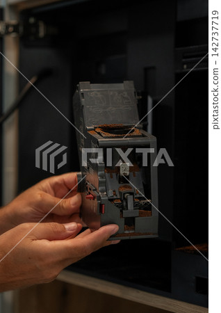 Hands holding coffee machine component for cleaning, showing interior parts and coffee grounds residue Hands holding coffee machine component for cleaning, showing interior parts and coffee grounds residue 142737719