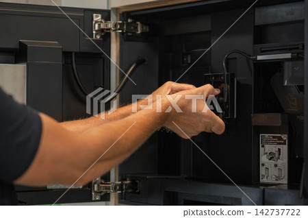 Hands of technician cleaning interior components of a coffee machine in modern kitchen setting Hands of technician cleaning interior components of a coffee machine in modern kitchen setting 142737722