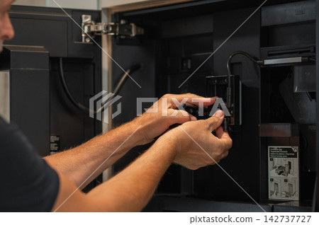 Hands of technician cleaning coffee machine components inside kitchen cabinet with tools visible Hands of technician cleaning coffee machine components inside kitchen cabinet with tools visible 142737727