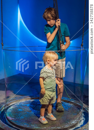 Young boys use hands-on exhibits with water and giant bubbles, showing STEM learning, curiosity and playful science education concept Young boys use hands-on exhibits with water and giant bubbles, showing STEM learning, curiosity and playful science education concept 142738878