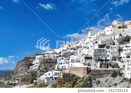 Santorini, Greece, Iconic White Buildings and Windmill on a Cliff Under Blue Sky Santorini, Greece, Iconic White Buildings and Windmill on a Cliff Under Blue Sky 142739120