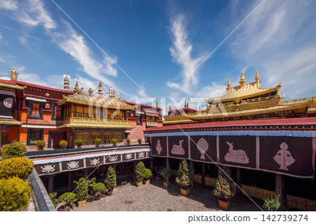 Traditional Tibetan Monastery Courtyard with Golden Roofs and Ornate Architecture Under Blue Sky Traditional Tibetan Monastery Courtyard with Golden Roofs and Ornate Architecture Under Blue Sky 142739274