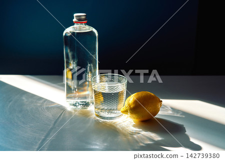 Refreshing water bottle and glass with lemon in sunlight Refreshing water bottle and glass with lemon in sunlight 142739380