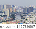 A panoramic cityscape shows dense layers of high-rise apartment buildings and low-rise rooftops beneath a hazy sky. 142739607
