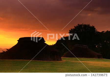 A thatched hut bathed in the morning light 142739673