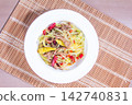 Bowl of salad with green papaya, meat, and spices on a bamboo mat 142740831