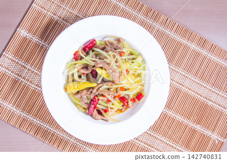 Bowl of salad with green papaya, meat, and spices on a bamboo mat Bowl of salad with green papaya, meat, and spices on a bamboo mat 142740831