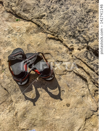 Pair of sandals resting on sunlit rocky surface, casting long shadow, top view summer footwear, outdoor travel adventure lifestyle High quality photo Pair of sandals resting on sunlit rocky surface, casting long shadow, top view summer footwear, outdoor travel adventure lifestyle High quality photo 142741146