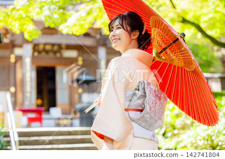 一位身穿和服的女子手持日式雨傘。 142741804