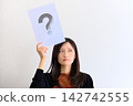 一位年輕女子頭頂上方有一個問號，神情憂慮地向上凝視（表示懷疑、思考或擔憂）。 142742555