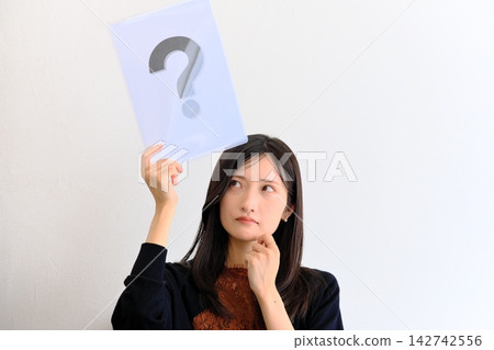 一位年輕女子頭頂上方有一個問號，神情憂慮地向上凝視（表示懷疑、思考或擔憂）。 142742556