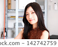 一位身著商務休閒服的年輕女員工在現代化的辦公室裡微笑。 142742759