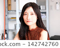 一位身著商務休閒服的年輕女員工在現代化的辦公室裡微笑。 142742760