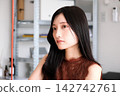 一位身著商務休閒服的年輕女員工在現代化的辦公室裡微笑。 142742761