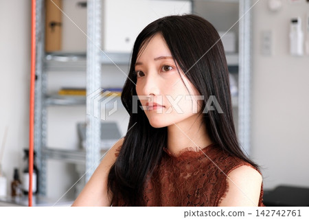 一位身著商務休閒服的年輕女員工在現代化的辦公室裡微笑。 一位身著商務休閒服的年輕女員工在現代化的辦公室裡微笑。 142742761