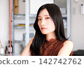 一位身著商務休閒服的年輕女員工在現代化的辦公室裡微笑。 142742762