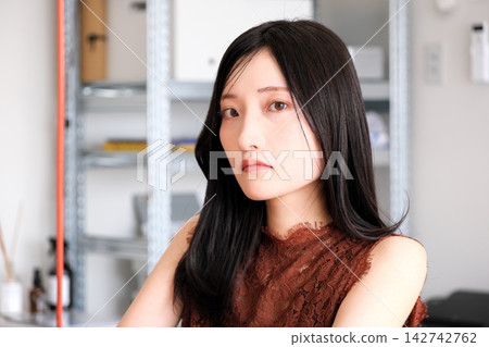 一位身著商務休閒服的年輕女員工在現代化的辦公室裡微笑。 142742762