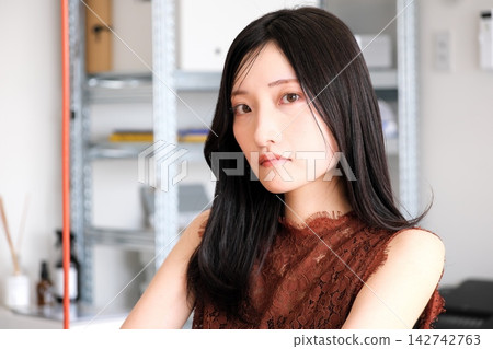 一位身著商務休閒服的年輕女員工在現代化的辦公室裡微笑。 一位身著商務休閒服的年輕女員工在現代化的辦公室裡微笑。 142742763
