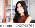 一位身著商務休閒服的年輕女員工在現代化的辦公室裡微笑。 142742764