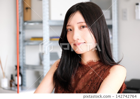 一位身著商務休閒服的年輕女員工在現代化的辦公室裡微笑。 一位身著商務休閒服的年輕女員工在現代化的辦公室裡微笑。 142742764