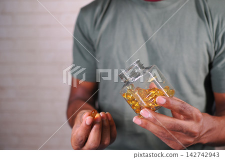Person holding a jar of dietary supplements in their hand Person holding a jar of dietary supplements in their hand 142742943