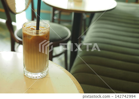 Coffee drink with ice on a table at a cafe during the day Coffee drink with ice on a table at a cafe during the day 142742994