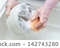 A housewife's hands washing dishes in the kitchen sink 142743280