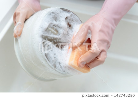 一位家庭主婦在廚房水槽裡洗碗。 142743280