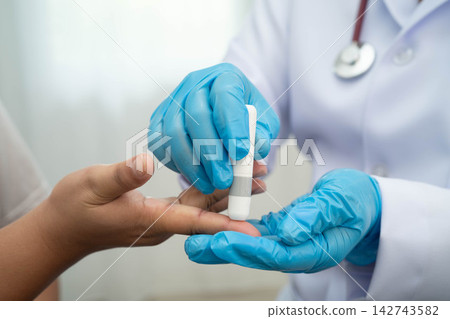 Doctor check diabetes from finger blood sugar level with finger lancet. Doctor check diabetes from finger blood sugar level with finger lancet. 142743582