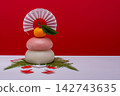 A photograph showing a real red and white rice cake ("kagami mochi") placed on the left, against a red and white background, without a sanbo (stand). 142743635