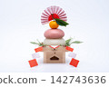 A photograph with a real red and white rice cake ("kagami mochi") placed in the center, against a white background, and on a low sanbo (stand). 142743636