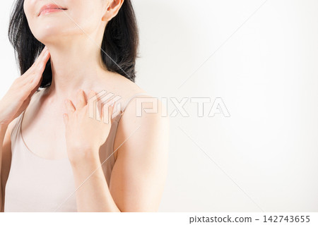 一位五十多歲的女性用雙手仔細照顧頸部和胸前肌膚;一位面無表情的中年美女,專注於抗衰老和護膚。 一位五十多歲的女性用雙手仔細照顧頸部和胸前肌膚;一位面無表情的中年美女,專注於抗衰老和護膚。 142743655