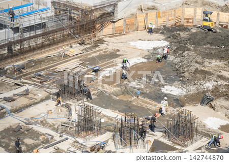 工人們正在大型建築物的地基施工現場測量位置和尺寸。 工人們正在大型建築物的地基施工現場測量位置和尺寸。 142744870