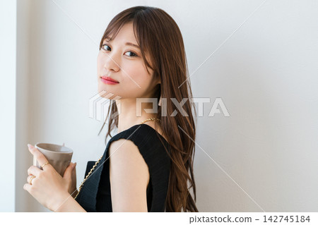 一位年輕女子手裡拿著馬克杯轉過身來。在家享受時尚咖啡館般的輕鬆時光。 142745184