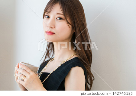 一位年輕女子手裡拿著馬克杯轉過身來。在家享受時尚咖啡館般的輕鬆時光。 142745185