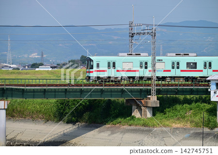Nishitetsu Railway crosses a railway bridge under a blue sky. Nishitetsu Railway crosses a railway bridge under a blue sky. 142745751