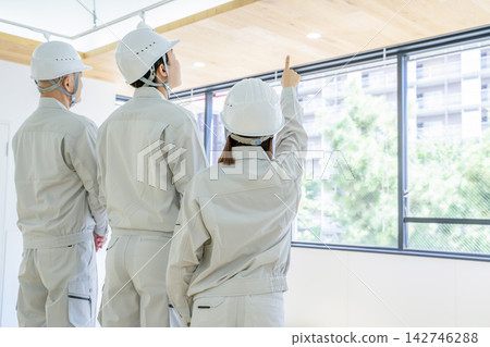 一名男子和一名女子身穿工作服,正在工地開會。 一名男子和一名女子身穿工作服,正在工地開會。 142746288