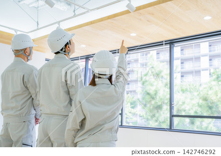 一名男子和一名女子身穿工作服,正在工地開會。 一名男子和一名女子身穿工作服,正在工地開會。 142746292