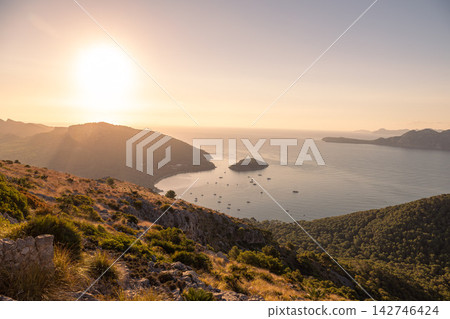 Scenic view of Mallorca northwest coastline at sunrise with rugged cliffs, calm Mediterranean Sea, distant horizon, and soft clouds lit by early morning light Scenic view of Mallorca northwest coastline at sunrise with rugged cliffs, calm Mediterranean Sea, distant horizon, and soft clouds lit by early morning light 142746424