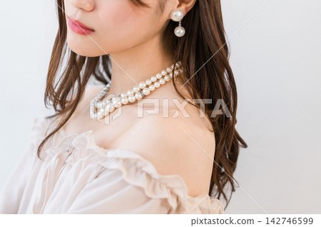 A woman wearing a pearl necklace and earrings. Elegant jewelry adorning her beautiful décolletage. A woman wearing a pearl necklace and earrings. Elegant jewelry adorning her beautiful décolletage. 142746599