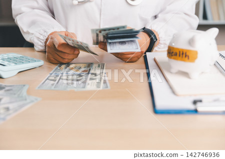 Healthcare professional counting dollar bills beside a calculator and piggy bank labeled Health, representing medical expenses, healthcare savings, budgeting, insurance costs, and financial planning. Healthcare professional counting dollar bills beside a calculator and piggy bank labeled Health, representing medical expenses, healthcare savings, budgeting, insurance costs, and financial planning. 142746936